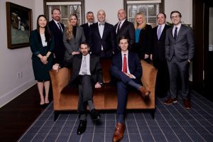 Group of attorneys in suits gathered around leather sofa